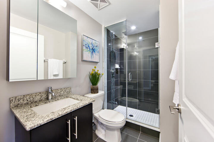 Small bathroom staged for a home sale with flowers and paintings for decor by StyleBite Staging in Toronto.