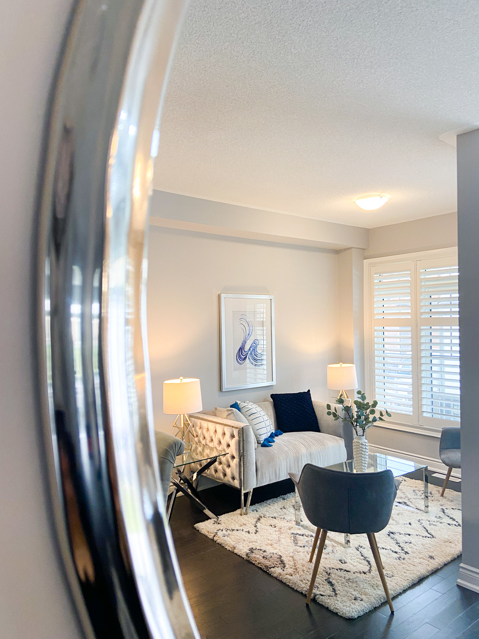 Living room with white furnitures, silver nightstands and blue decor staged by StyleBite Staging consultant for a sale in Toronto
