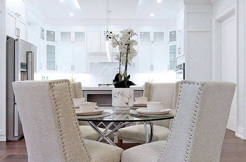 Silver kitchen staged with beige chairs and glass round table by StyleBite condo and home staging services in Toronto
