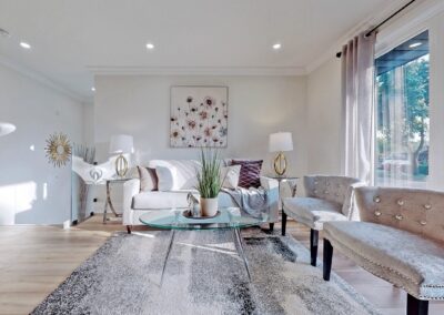 Living area staged with white furniture, purple and gold decor, large carpet and side lamps by StyleBite home staging company in Toronto.