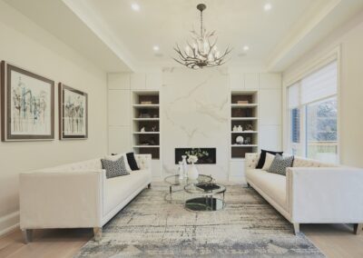 marble living room wall with fireplace staged with white couches by StyleBite home staging services in Toronto.