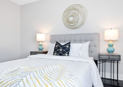 Guest room with white walls staged with turquoise lamps with gold decor by StyleBite home staging services in Toronto.