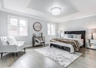 Bedroom staged with white chair, mirrored furnitures and round mirror by StyleBite condo and home staging services in Toronto