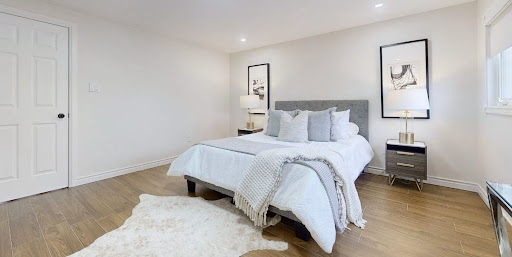 Minimalist bedroom with a gray upholstered bed, white bedding, matching nightstands, and light wood flooring