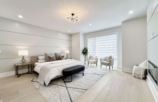 Staged bedroom with neutral decor, upholstered bed, and built-in wall fireplace